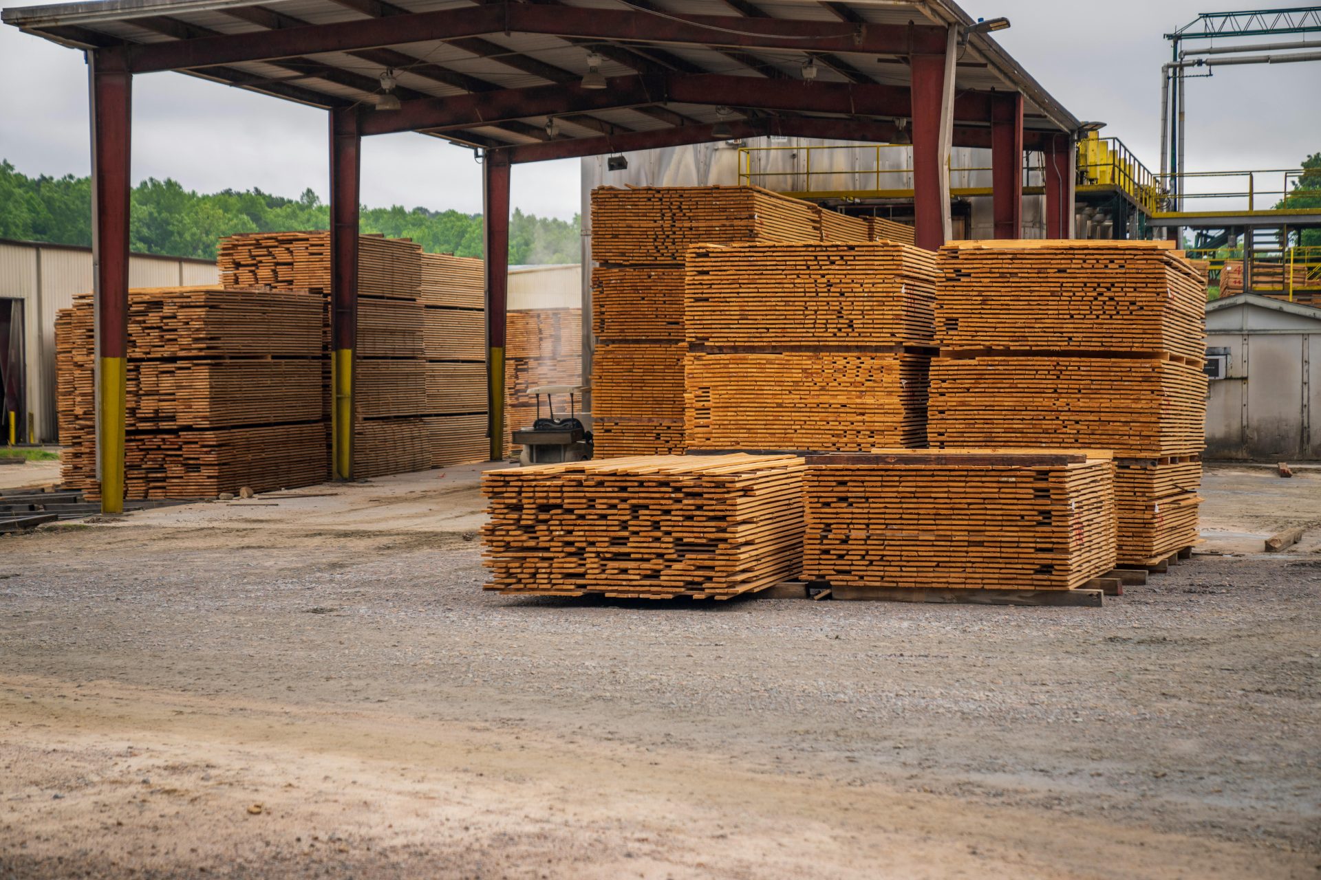 Montones de tablones de madera en un aserradero al aire libre, donde se exhiben materiales de construcción.